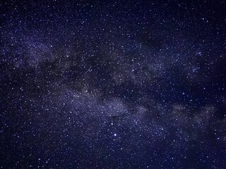 Obraz premium Photograph captures the breathtaking beauty of a starry night sky. The Milky Way stretches across the frame like a cosmic river, with stars twinkling against the deep, inky darkness of the universe.