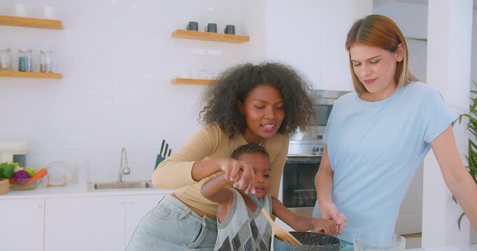 A joyful family scene with a mother child and friend cooking together in a bright modern kitchen, Enjoying Quality Time Preparing a Meal, highlighting togetherness and culinary fun.