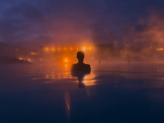Tourist relaxing in geothermal pool at dusk in iceland