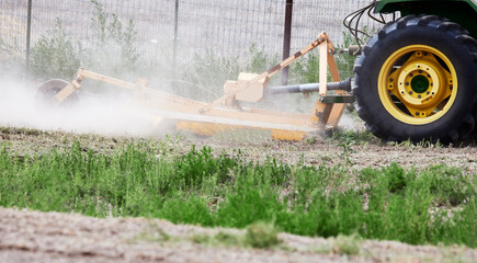 Large tractor mower attachment mowing a field of weeds