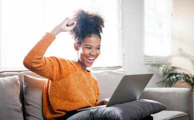 Excited black woman feel euphoric or happy reading good news online, sits on couch at home