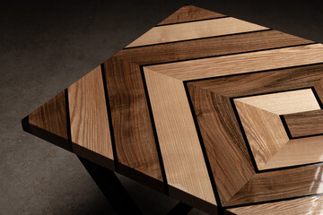 Expensive vintage furniture. The table is covered with epoxy resin and varnished. Luxury quality wood processing. Wooden table on a dark background. Swirling geometric patterns in the form of a maze.