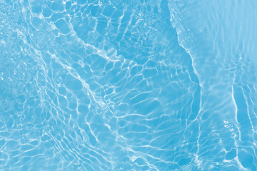 Blue water with ripples on the surface. Defocus blurred transparent blue colored clear calm water surface texture with splashes and bubbles. Water waves with shining pattern texture background.