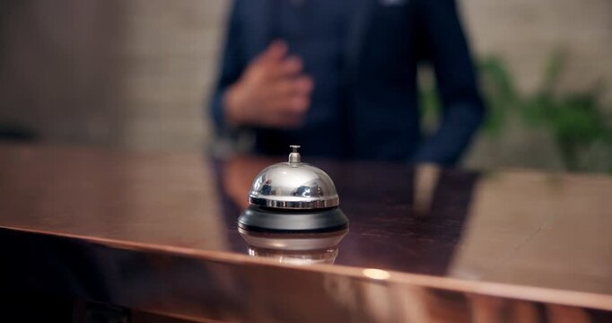 Hospitality, bell and hand in hotel with man, service and concierge at reception or desk. Assistance, alert and arrival of guest in lobby for holiday, vacation and butler or doorman for tourism