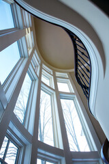 Looking up at a modern interior of large windows and spiral staircase as a beautiful vertical image