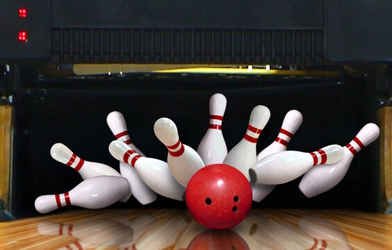Bowling strike hit with ball hitting ten pins in the alley