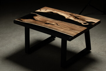 Expensive vintage furniture. The table is covered with epoxy resin and varnished. Luxury quality wood processing. Wooden table on a dark background. Black river made of epoxy resin.