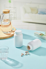 On pastel table, white medicine bottles decorated with glass cup, daily medicine box and wooden tray. Medicine bottles empty label for design and advertising