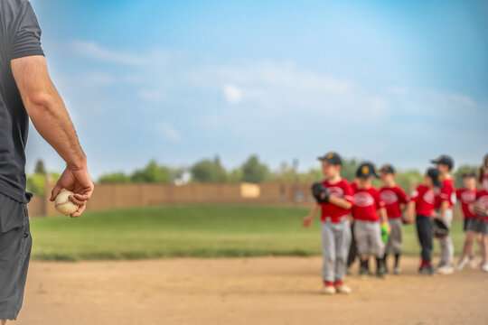 Selective focus on a coach getting ready to toss a ball to a child during practice 