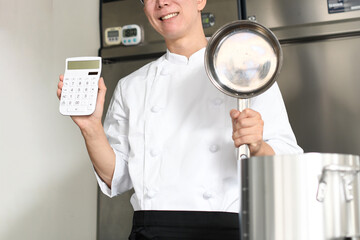 鍋と電卓を持ち悩むアジア人の男性調理師