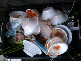 waste foam and plastic trays, waste foam food trays white trash piles in dirty black plastic bins,...