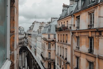 Fototapeta premium Paris apartment balcony view of narrow streets and historic buildings on a cloudy day with muted colors.
