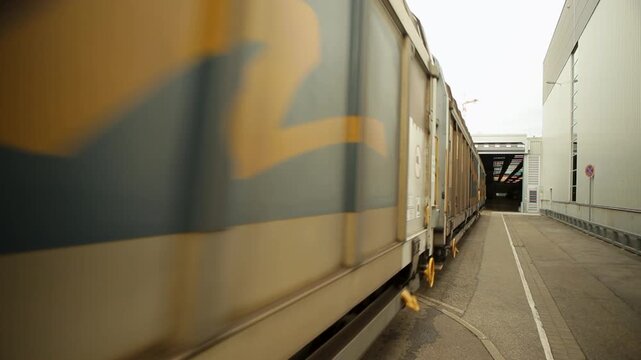 Freight train exiting industrial building on a clear day