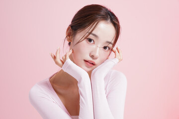 ピンク背景で撮影をした若い女性のキャッチーなビューティー...