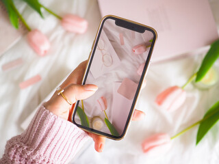 ピンクと白を基調とした可愛いスマートフォンを持つ女性の手元、フェミニンなスマートフォンのイメージ