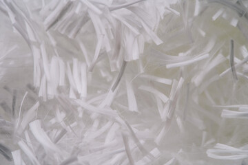 Close-up of white fiberglass strands in a chaotic, tangled arrangement. The image highlights the fine, fibrous texture of the material.