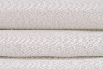 Close-up of folded fiberglass fabric with visible metal threads, highlighting its detailed, textured weave and layered arrangement.