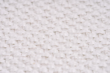 Close-up of white woven fabric with visible metal threads, highlighting the intricate texture and pattern in a macro view.