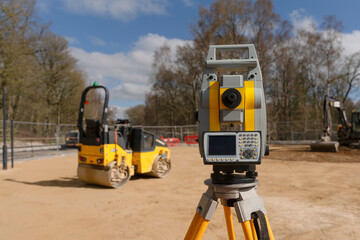 Surveying Equipment in a Construction Site With Machinery and Trees Under  Blue Sky