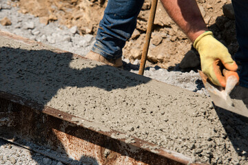 Worker Applying Concrete to  Foundation During Construction at  Outdoor Site on Sunny Day