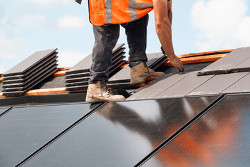 Construction Worker Installing Solar Panels on Rooftop Under Sky During Daytime