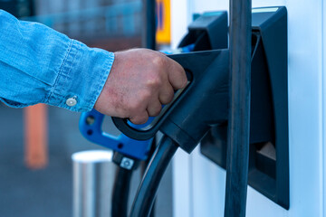 Person Charging Their Vehicle at Electric Vehicle Charging Station During Daylight