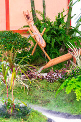 Minimal Japanese garden in home with small stone lantern and bamboo fountain and moss and flowers.

