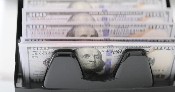 Bank worker hands operate banknote counter machine preparing cash for client. Specialized device rapidly counts dollar bills without errors
