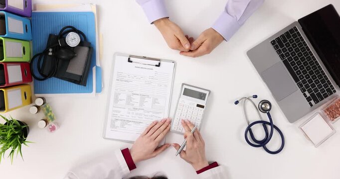 Doctor considers calculator for medical expenses for patient top view