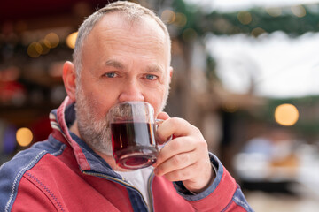 Man Enjoying Warm Beverage at Cozy Outdoor Café During Chilly Afternoon