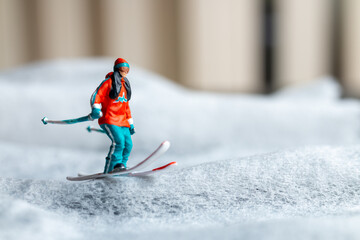 A miniature figurine of a skier in motion skiing across a white snowy landscape