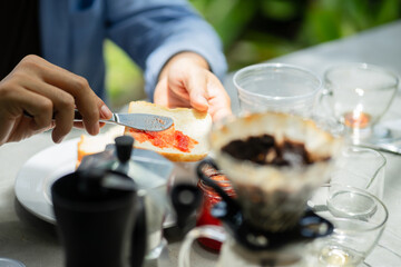 Close-up of a man drinking coffee and eating at a bakery in the park.