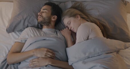Beautiful young couple man and woman sleeping lying in bed and hugging in dark bedroom early morning. Relationship and relaxation concept. - Powered by Adobe