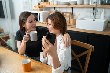 Two women read books, use laptops to work, kitchen