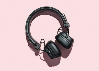 Full-size headphones. Modern devices for listening to music, pink background. Studio shot.