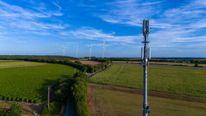 Rural Telecommunication Tower Amid Expansive Farmland and Wind Turbines and 5G