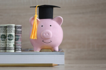 Graduation hat on blue piggy bank with stack of coins money on wooden background, Saving money for education concept