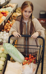 Cheerful teen girl shopping for organic fruits without plastic bags in local food store. Vegan zero waste girl choosing fresh fruits and vegetables in supermarket. Part of a series