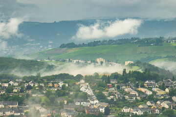 Obraz premium Dark storm clouds over the city of Trier in Germany, landscape with vineyards, agriculture field and forest, rainy weather in summer