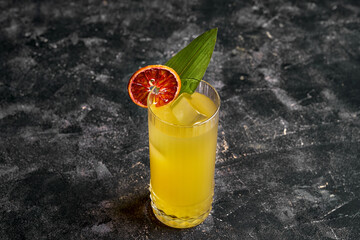 A refreshing citrus cocktail in a tall glass, garnished with a orange slice and a green leaf