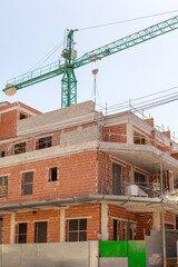 Vivid capture of construction site showcasing building in progress with brickwork and crane lifting materials. Ideal for real estate, development projects, and construction industry themes.