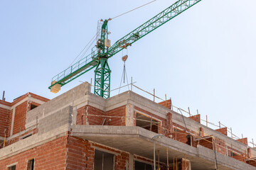 Vivid capture of construction site showcasing building in progress with brickwork and crane lifting...