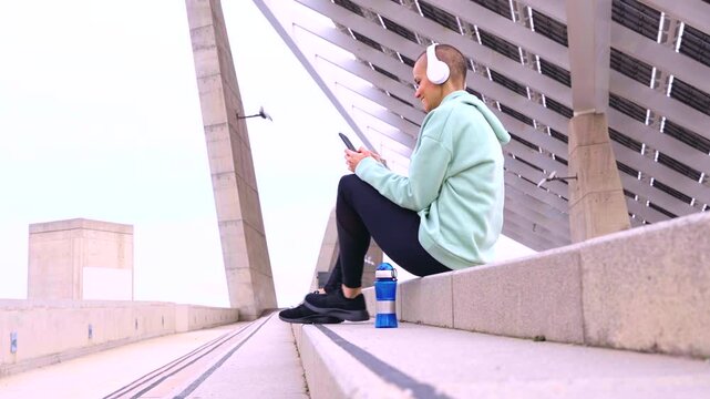  A female runner takes a break to use an app on her smartphone outdoors.