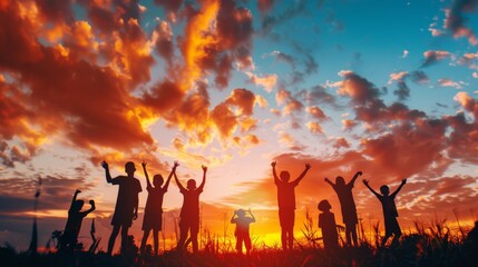 Fototapeta premium A vibrant sunset scene with silhouettes of people raising their hands in celebration, set against a dramatic, fiery sky.