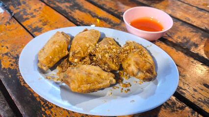 Fried Chicken Wings with Fish Sauce, Fried chicken wings in white dish on wooden table , Appetisers food.