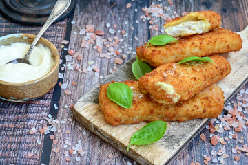 Close up of   Crispy breaded  deep fried fish fingers with breadcrumbs served  with remoulade sauce and  lemon Cod Fish Nuggets on rustic wood table background