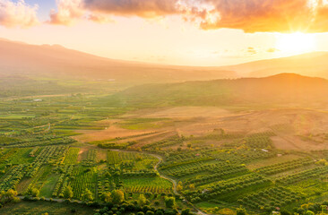 scenic rustic landscape with green hills and farms in a mountain valley during colorful cloudy sunset