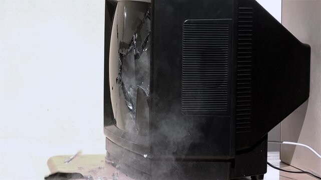 A thrown hammer breaks the screen of an old television