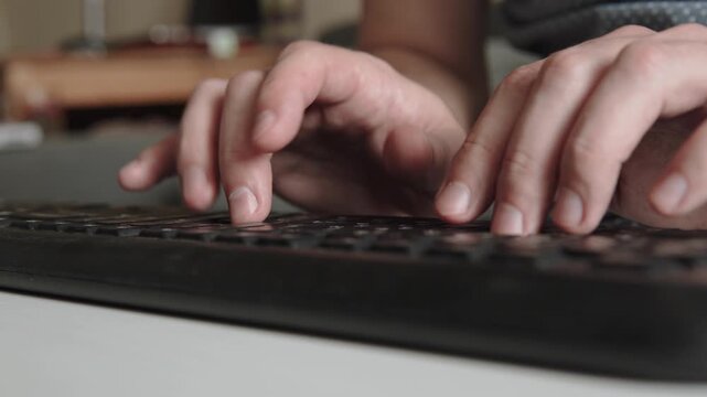 Caucasian man typing text on keyboard with both hands close up. Entering data and pressing keys on wireless black keyboard. Writing email by freelance copywriter.