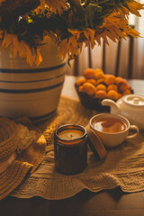 Candle lit amidst a cozy setup with tea, sunflowers, and apricots, exuding warmth and tranquility